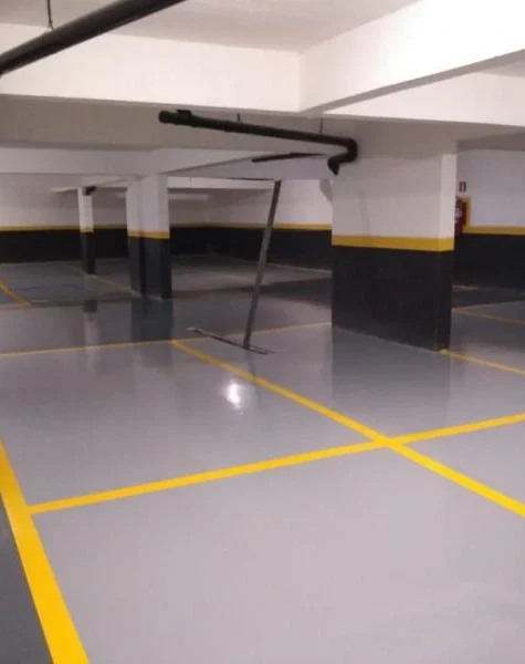 Estacionamento comercial com piso epóxi de alta resistência — demarcação de vagas em cores contrastantes, sem manchas de óleo